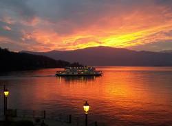 Il traghetto nel lago infuocato dal tramonto